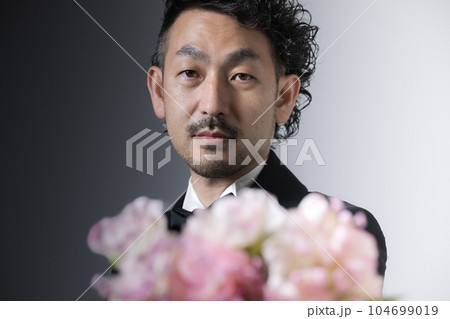 花束をプレゼントするフォーマルな髭の男性 花束をプレゼントするフォーマルな髭の男性 104699019