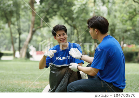 Young Asian Volunteers with garbage bags cleaning park area. Ecology, Charitable organization concept Young Asian Volunteers with garbage bags cleaning park area. Ecology, Charitable organization concept 104700870