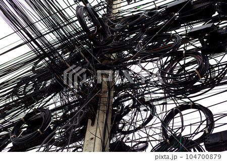 Many electrical cable are tangled on an electric pole. 104700879