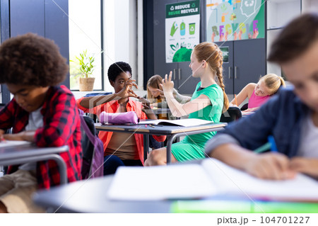 Happy, diverse female school teacher and schoolgirl practicing sign language in class Happy, diverse female school teacher and schoolgirl practicing sign language in class 104701227