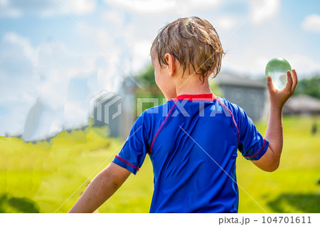 Young Caucasian boy taking aim to throw a water balloon.  104701611