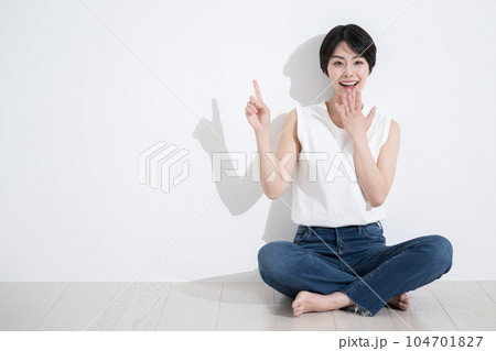 カジュアルな姿で座って指を差す女性のカメラ目線 カジュアルな姿で座って指を差す女性のカメラ目線 104701827