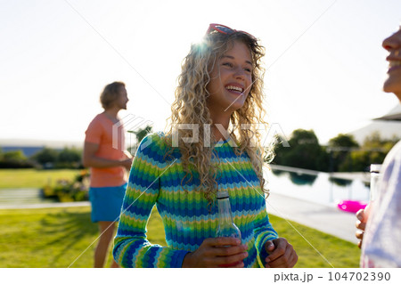 Happy diverse group of friends having party, drinking beer and talking in garden 104702390