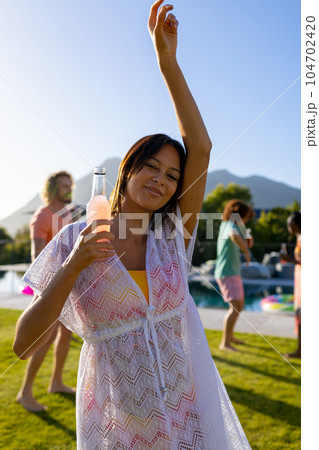 Portrait of happy biracial woman dancing with her friends at party in garden 104702420