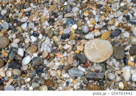 Crushed stone on the seashore. Selective focus on object. The stones were laid on the ground in the garden as a background. Background blur. Pebble stones background. Crushed stone on the seashore. Selective focus on object. The stones were laid on the ground in the garden as a background. Background blur. Pebble stones background. 104703442