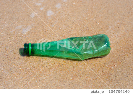 Green plastic bottle on the beach 104704140