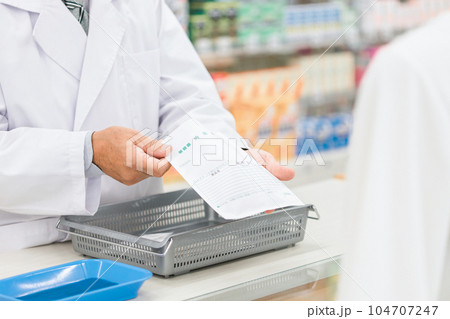 薬袋を客に渡す調剤薬局で働く薬剤師の男性 薬袋を客に渡す調剤薬局で働く薬剤師の男性 104707247