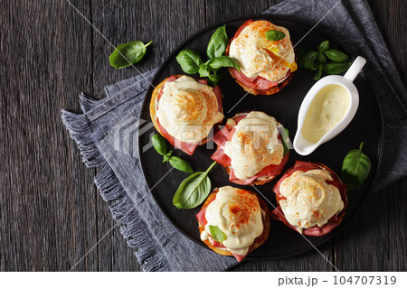 Eggs Benedict on black plate, top view Eggs Benedict on black plate, top view 104707319