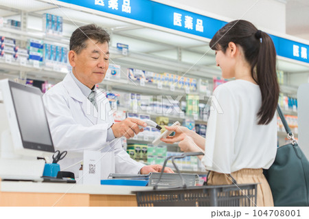 薬局でスマホ決済をする女性と薬剤師・調剤師の男性 薬局でスマホ決済をする女性と薬剤師・調剤師の男性 104708001