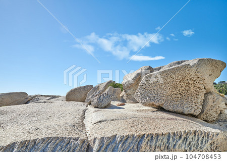 Big boulders on a rocky coast outside on a summer day. Landscape view of a beautiful beach and seashore under a clear blue sky. A natural seaside environment and marine habitat with copy space Big boulders on a rocky coast outside on a summer day. Landscape view of a beautiful beach and seashore under a clear blue sky. A natural seaside environment and marine habitat with copy space 104708453