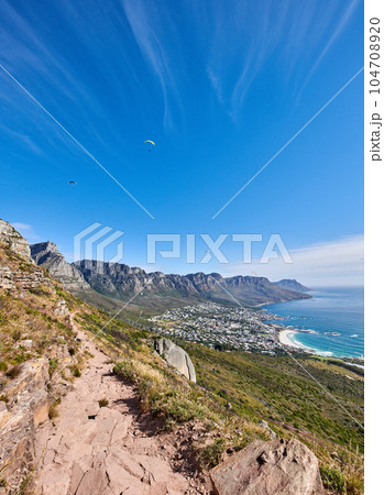Famous mountain hiking trail with copy space, rough rocks or stones leading to scenic view of Twelve Apostles in Cape Town. Landscape of ocean, sea and coastal city with blue sky from nature reserve 104708920