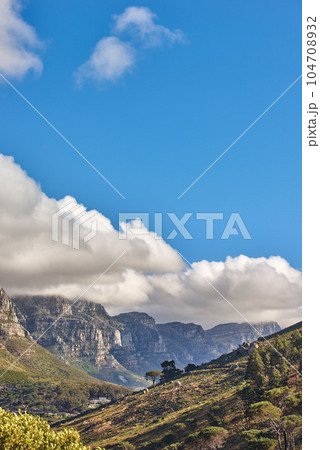 Landscape of the 12 apostles mountain range in Cape Town, South Africa looking beautiful with blue sky, white and grey clouds. Stunning view of mountains and nearby trees on a hill with copy space 104708932
