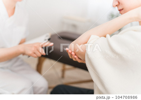 整形外科でテニス肘・肘の怪我をして悩む患者とカウンセリング・診察・問診する医師・看護師・カウンセラー 104708986