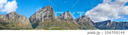 Twelve Apostles at Table Mountain in Cape Town against a blue sky background from below. Breathtaking view of plants and shrubs growing around a majestic rocky valley and scenic landmark in nature Twelve Apostles at Table Mountain in Cape Town against a blue sky background from below. Breathtaking view of plants and shrubs growing around a majestic rocky valley and scenic landmark in nature 104709144
