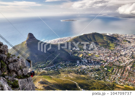 Stunning city, mountain and ocean aerial view with cloudy sky background and copy space. Beautiful landscape of the calm sea on the horizon and Lions Head at a sightseeing location in Cape Town 104709737