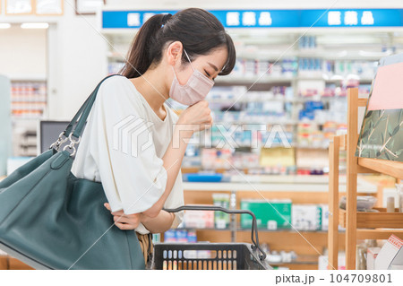 薬局・ドラッグストアで買い物をする体調不良・咳をするマスク姿の女性 104709801