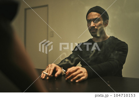Man in investigation, smoking and detective in interrogation room with criminal, suspect or interview with a gangster. Police officer, questioning and statement of truth and person with cigarette 104710153