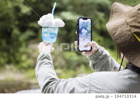 キャンプ場で映えドリンクをスマホで撮影する若い女性 キャンプ場で映えドリンクをスマホで撮影する若い女性 104710314