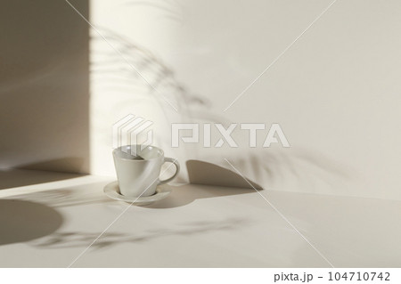 A room with various objects such as warm sunlight, shadows of grass leaves, a vase on a table, and cups 104710742