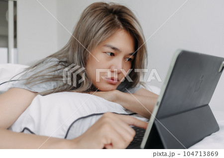 Woman working online on the tablet computer on the bed in the morning. Woman working online on the tablet computer on the bed in the morning. 104713869