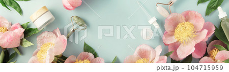 Top view of natural cosmetics and pink peonies on pastel blue background with white card for invitation, logo or design 104715959