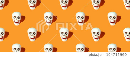 Halloween decorations. Human skull pattern with the orange background 104715960