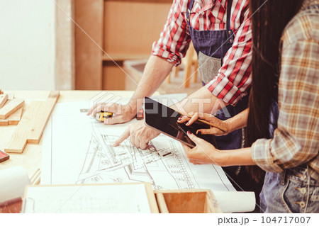 professional architect working with floor plan wooden home furniture and renovate in workshop talking consulting with engineer team. professional architect working with floor plan wooden home furniture and renovate in workshop talking consulting with engineer team. 104717007