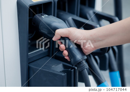 charging EV car electric vehicle clean energy for driving future. hand holding charger head station. 104717044