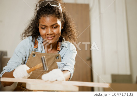 Smart happy woman wood working hammer on wooden board project home furniture diy in workshop. 104717132