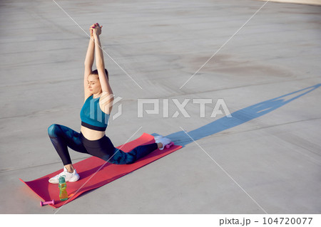 Top view image of young woman with slim, fit body training on fitness mar outdoors on warm summer day. Stretching and yoga Top view image of young woman with slim, fit body training on fitness mar outdoors on warm summer day. Stretching and yoga 104720077