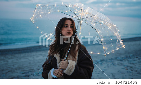 Glowing umbrella of a girl walking on the beach in the night outdoor Glowing umbrella of a girl walking on the beach in the night outdoor 104721468