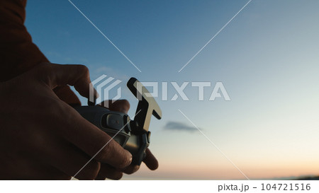 Silhouette of hand pilot of an fpv drone at sunset 104721516