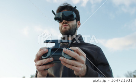 Man pilot a drone with technologic virtual reality glasses and remote controller Man pilot a drone with technologic virtual reality glasses and remote controller 104721931