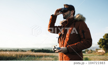 Man landing his fpv drone with virtual reality goggles on the head 104721983
