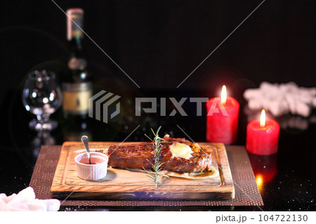 Rib eye steak on the New Year's table. Steak rib eye roast on a wooden board with sauce and salt. Beef steak on wooden plate. Rib eye steak on the New Year's table. Steak rib eye roast on a wooden board with sauce and salt. Beef steak on wooden plate. 104722130