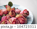 Several pink dried rose buds on a plate as interior decor. Group of beautiful dead flowers close-up as a concept of passed time, sadness, depression. Selective focus on the foreground 104723311