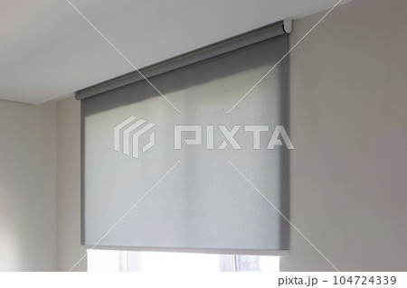 Roller blinds automatic close-up on the window. Selective focus. Motorized shades. Gray color curtain, texture fabric. City outside the window. Roller blinds automatic close-up on the window. Selective focus. Motorized shades. Gray color curtain, texture fabric. City outside the window. 104724339