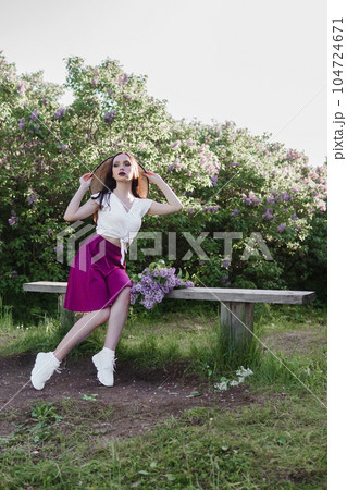 A fashionable girl with dark hair, a spring portrait in lilac tones in summer. Bright professional makeup. A fashionable girl with dark hair, a spring portrait in lilac tones in summer. Bright professional makeup. 104724671