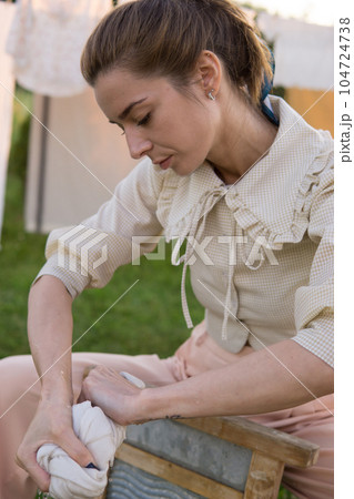 Laundry day. A woman hangs linen and towels on a tree in the courtyard of a village house. 104724738