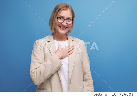 kind mature woman in a stylish image holds her hands near her heart on a bright studio background kind mature woman in a stylish image holds her hands near her heart on a bright studio background 104726003