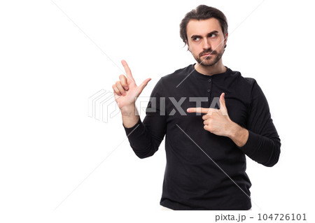 young bearded brutal european macho man with ear piercing and with black hair points his finger to 104726101