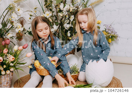 Two girls in a beautiful Easter photo zone with flowers, eggs, chickens and Easter bunnies. Happy Easter holiday. Two girls in a beautiful Easter photo zone with flowers, eggs, chickens and Easter bunnies. Happy Easter holiday. 104726146