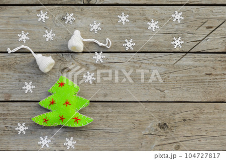 Handmade Christmas toys lie on a wooden background. A green herringbone sewn from felt and white hats knitted from wool do it yourself. 104727817