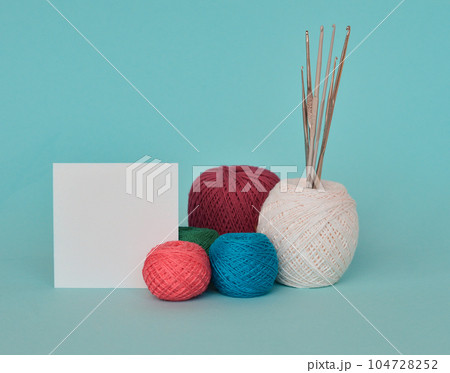 A closeup shot of red, purple, and blue knitting yarns and crochet hooks 104728252
