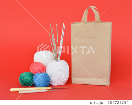A closeup shot of red, purple, and blue knitting yarns and crochet hooks 104728254