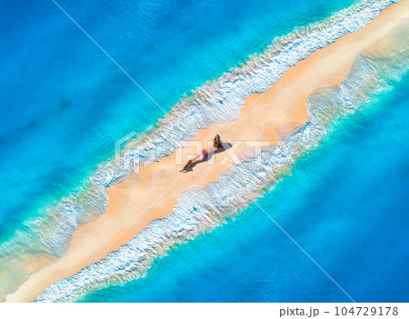 Aerial view of the beautiful young lying woman on the sandy beach 104729178