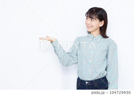 白い背景の前で紹介をしている30代の女性 白い背景の前で紹介をしている30代の女性 104729930