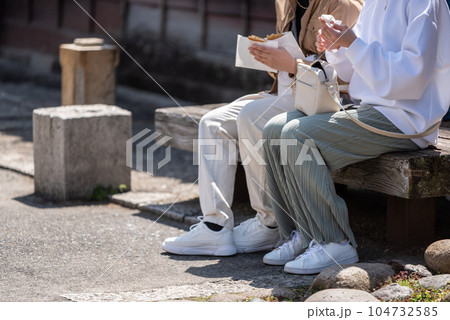 観光地でソウルフードを買い食いする若い女性　顔なし 104732585
