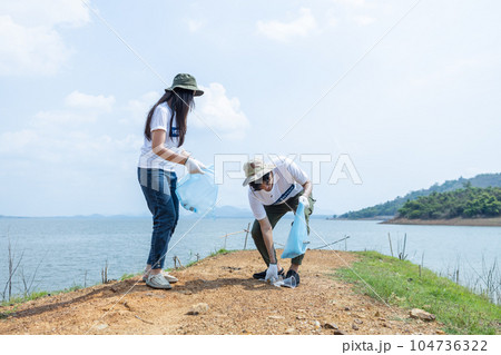 man and woman volunteers holding rubbish bags. clean up garbage in tourist attractions man and woman volunteers holding rubbish bags. clean up garbage in tourist attractions 104736322