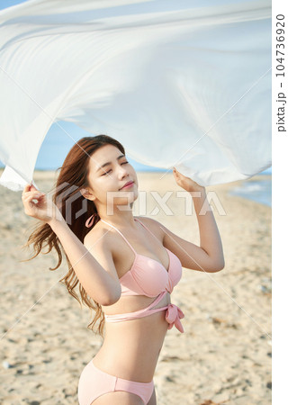 young woman in swimsuit posing on beach 104736920